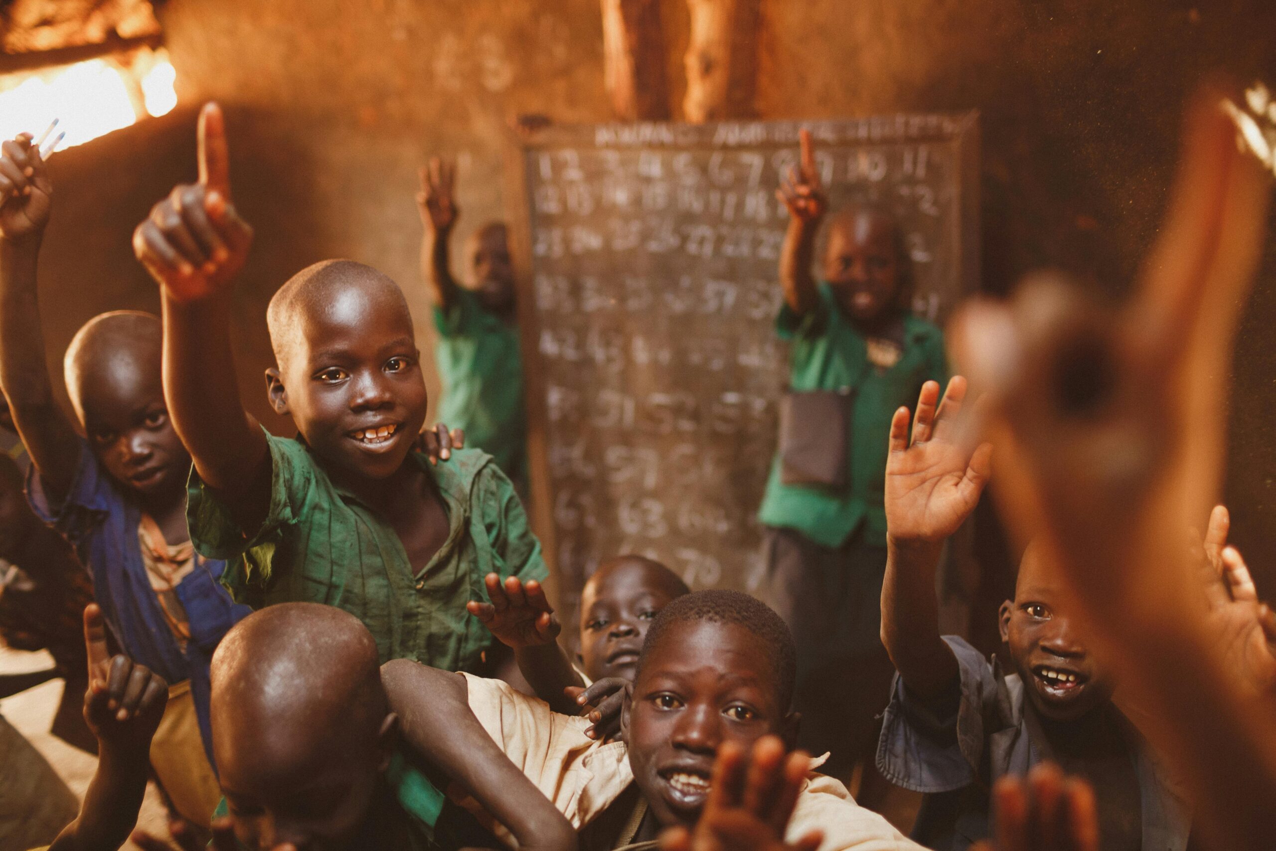 a group of children raising their hands in a classroom